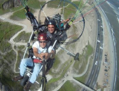 Action Valley-Paratrike over seawalls of green coast of Lima
