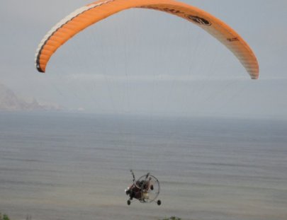 Action Valley-Paratrike over seawalls of green coast of Lima